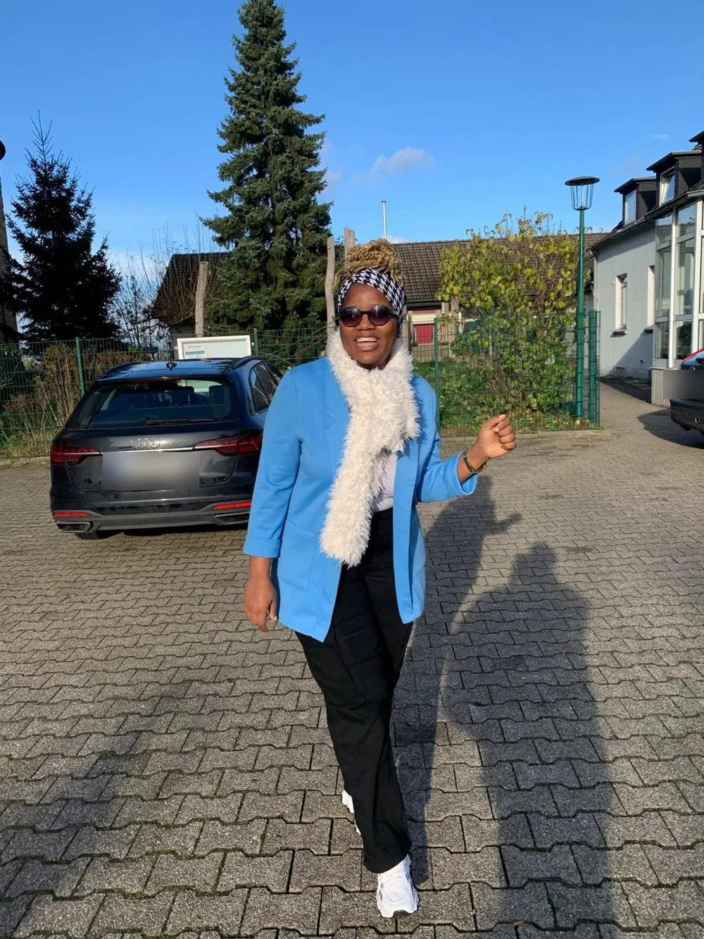 Une apprenante souriante en veste bleue sur un parking en Allemagne