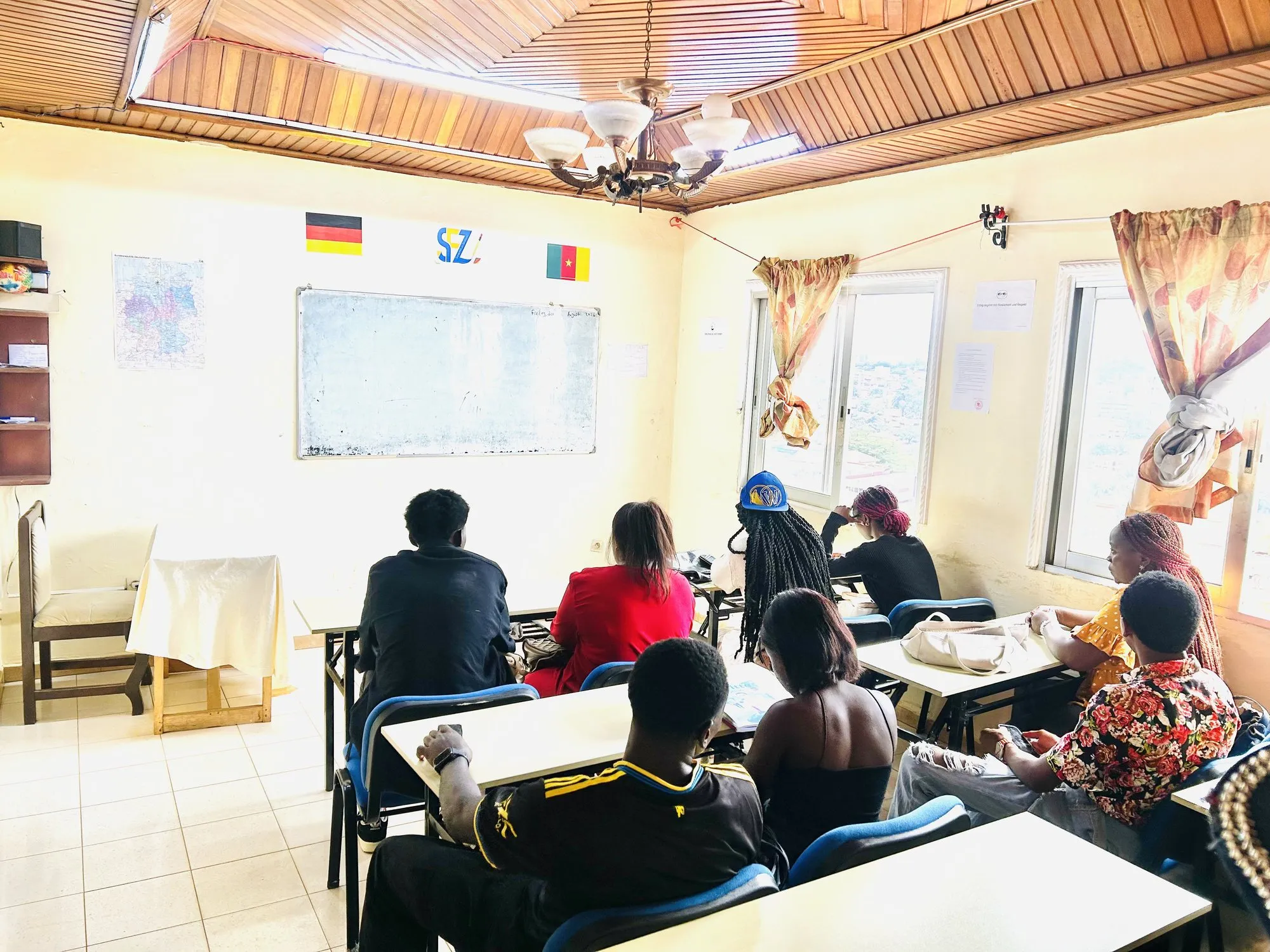 Apprenants en cours d’allemand dans une salle lumineuse du centre, avec les drapeaux allemand et camerounais au mur