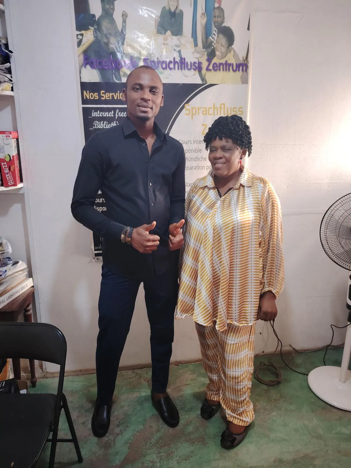 Marie-Noelle Che Neba et Théophile Mebou, pouces levés, devant la bannière du centre à Douala