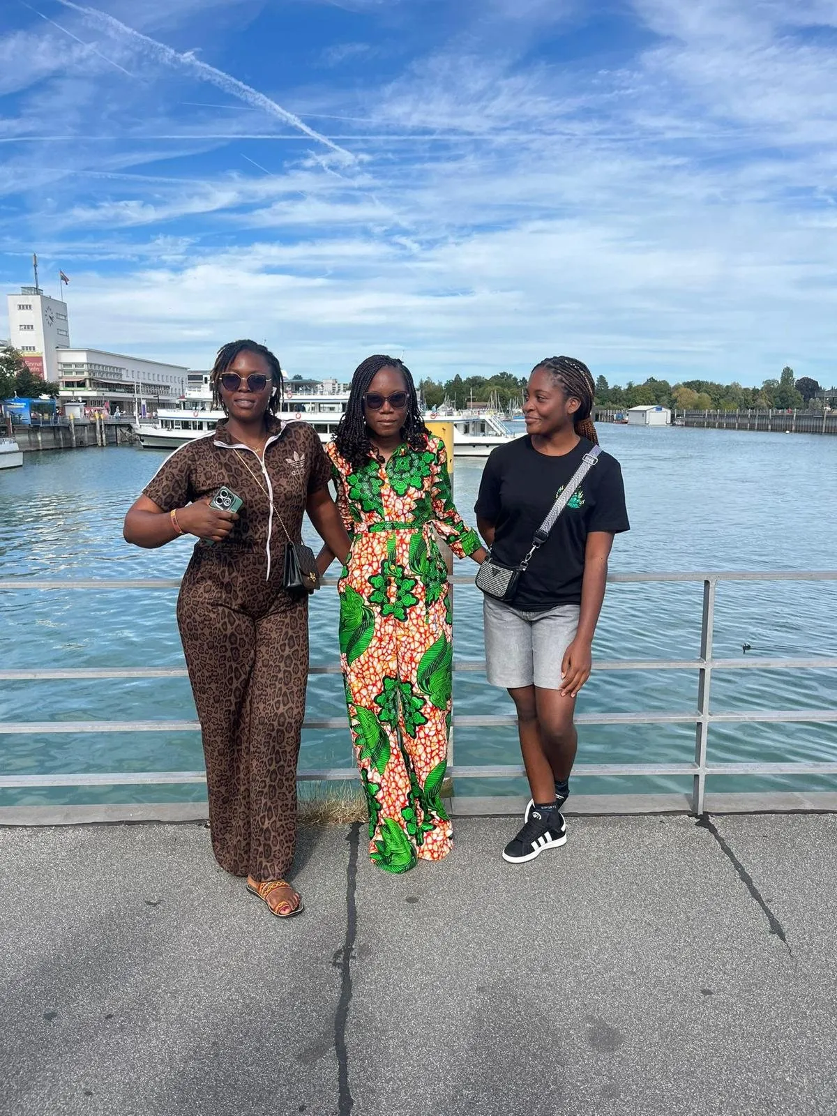 Trois jeunes femmes posent au bord du lac de Constance, à Friedrichshafen, avec le port en arrière-plan